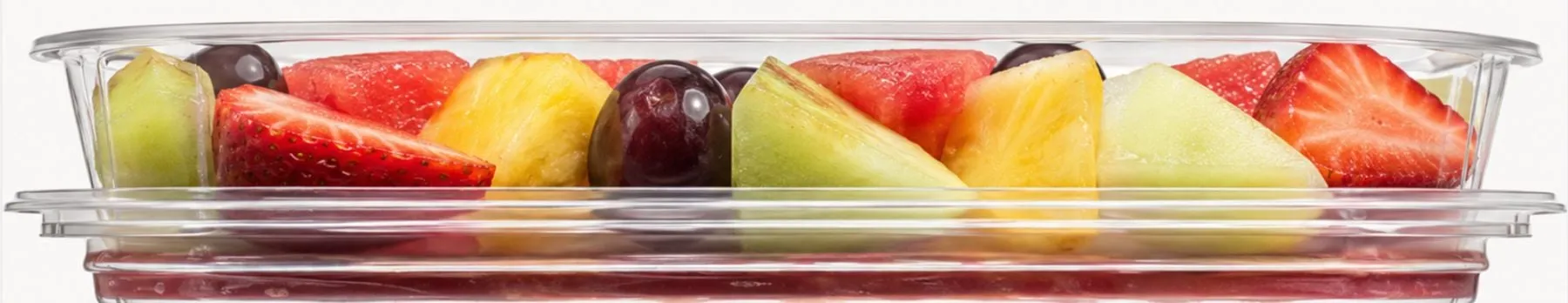 A long clear tray of cut fruit seen from above