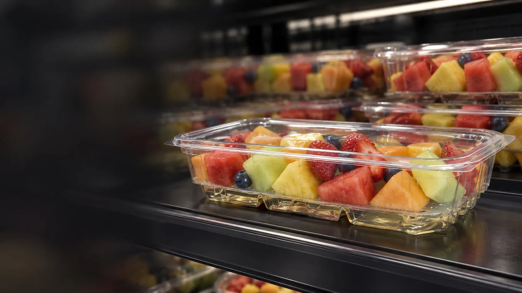 Cut fruit packed dry in clear Lucid Infinity trays in the retail case, juice collected below