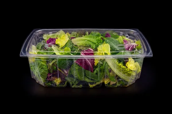 Leafy greens in a clear Lucid tray on black